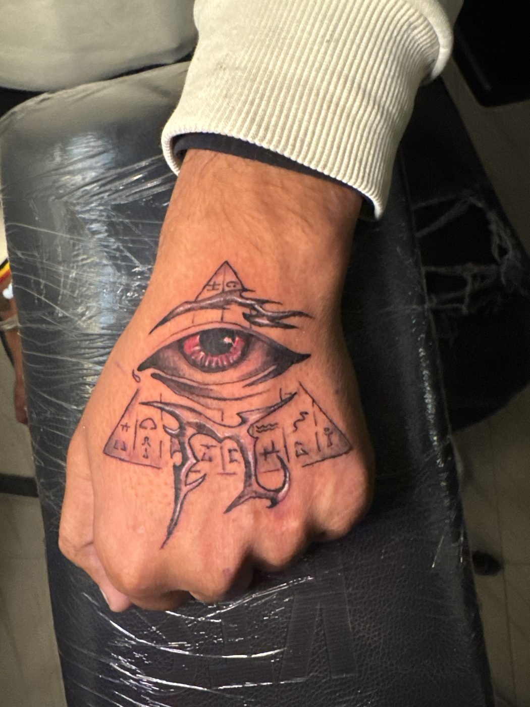 All-seeing eye pyramid hand tattoo with hieroglyphs