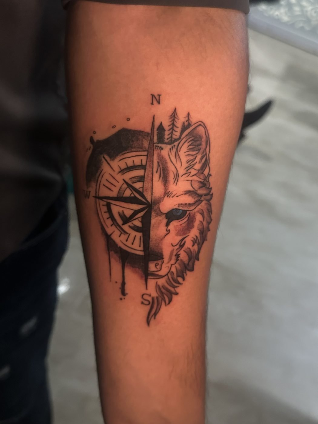 Wolf and compass split-design forearm tattoo